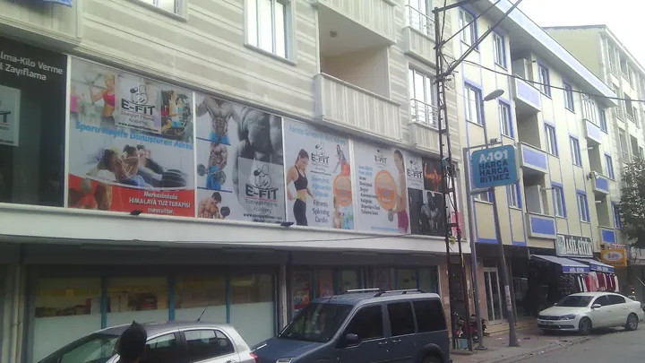 E-Fit geniş vitrin baskıları — Fitness salonunun bölmeli cam cephesindeki büyük görseller.