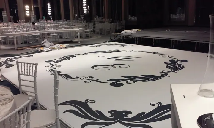 Düğün salonu zemin grafiği — Sahne önündeki geniş zeminde siyah desen ve monogram uygulaması.